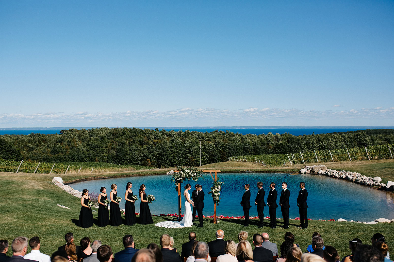 Wedding ceremony at Verterra Winery with scenic vineyard and lake backdrop.